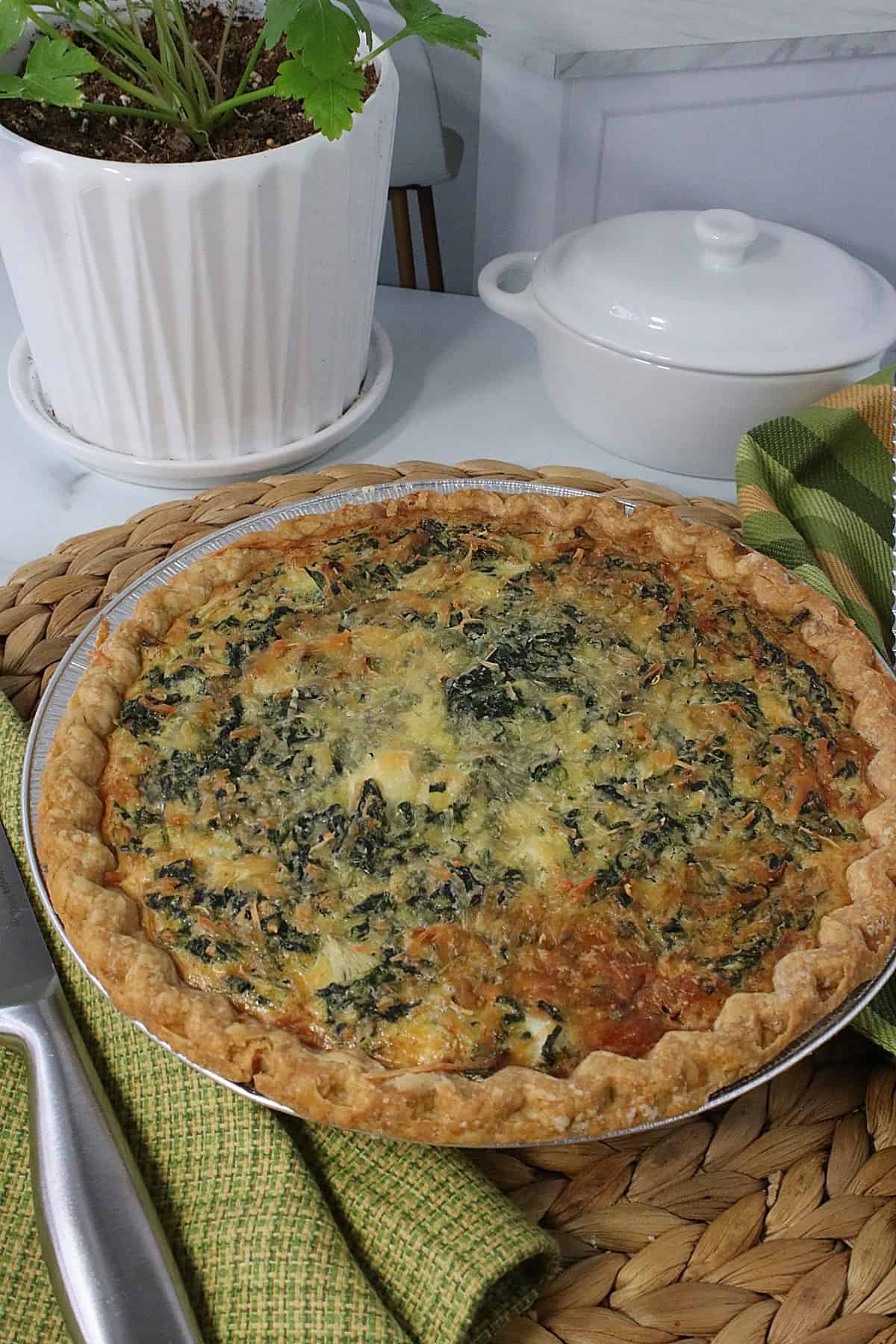 A golden brown baked Spinach and Artichoke Quiche in a pie pan.