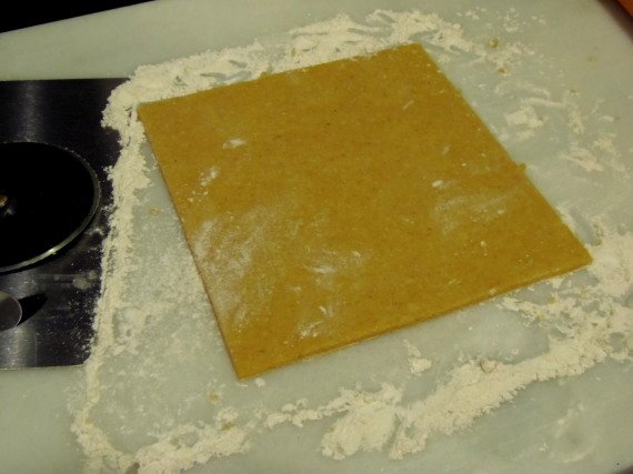 A rolled slab of homemade cornbread pastry dough on a floured surface.
