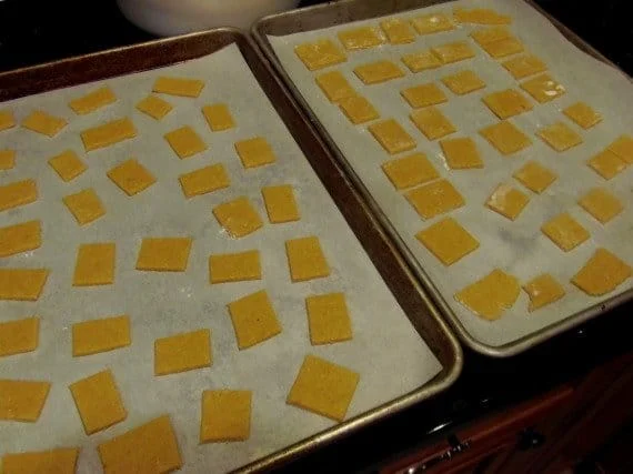 Two baking sheets filled with unbaked Homemade Cornbread Crackers.