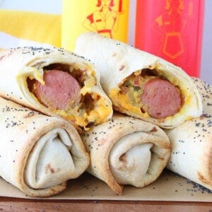 A stack of Burrito Dogs with some ketchup and mustard in the background.