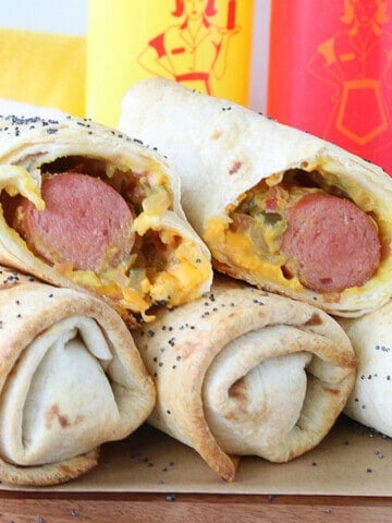 A stack of Burrito Dogs with some ketchup and mustard in the background.