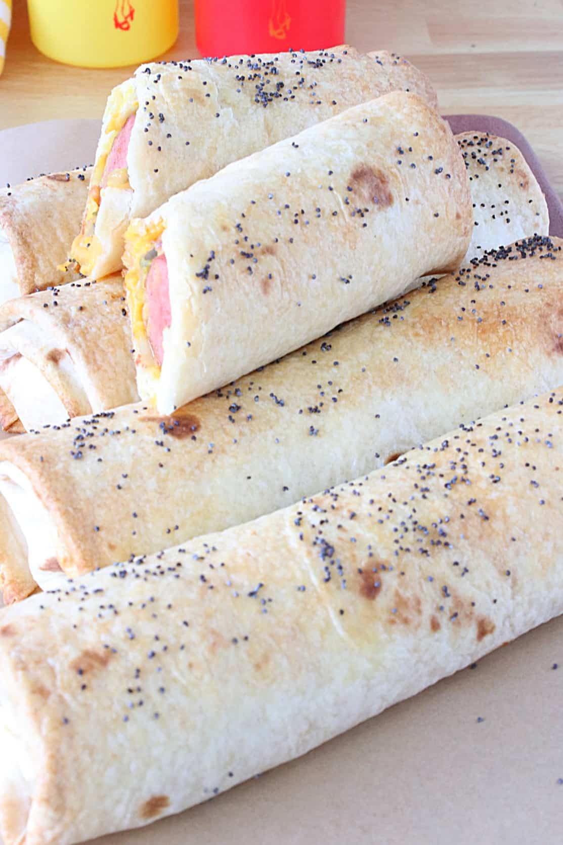 A stack of Burrito Dogs topped with poppy seeds.