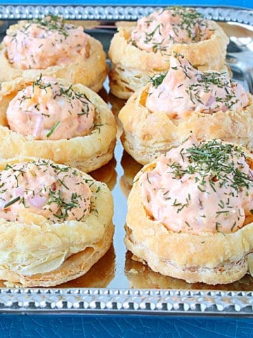 Pretty Ham and Cheese Puff Pastry Appetizer Cups topped with dill on a pretty silver platter.