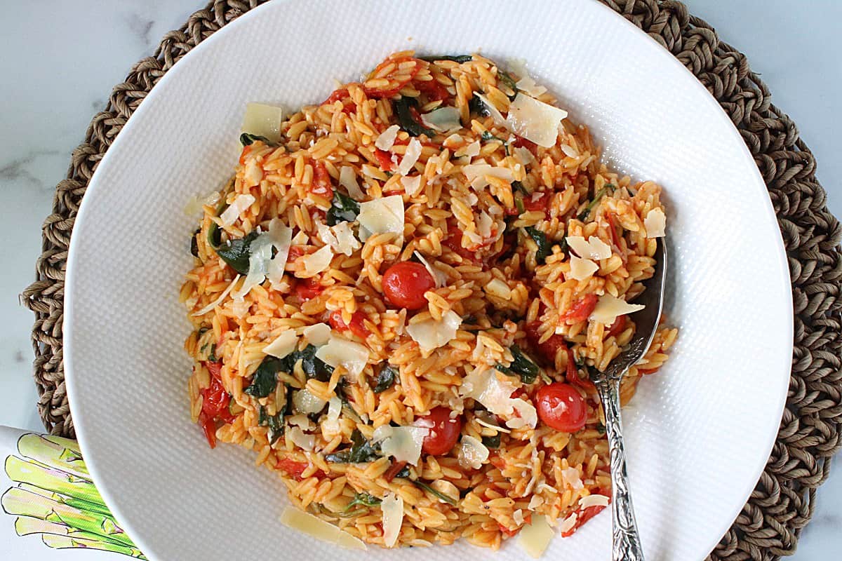 Orzo Pasta with Tomatoes and Spinach in a bowl topped with Parmesan cheese.