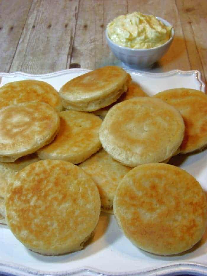 Golden brown crumpets on a white platter.