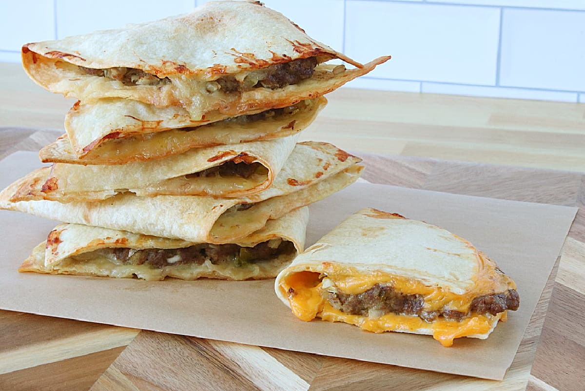 A stack of Burgerdillas with melted cheese on a wooden cutting board.