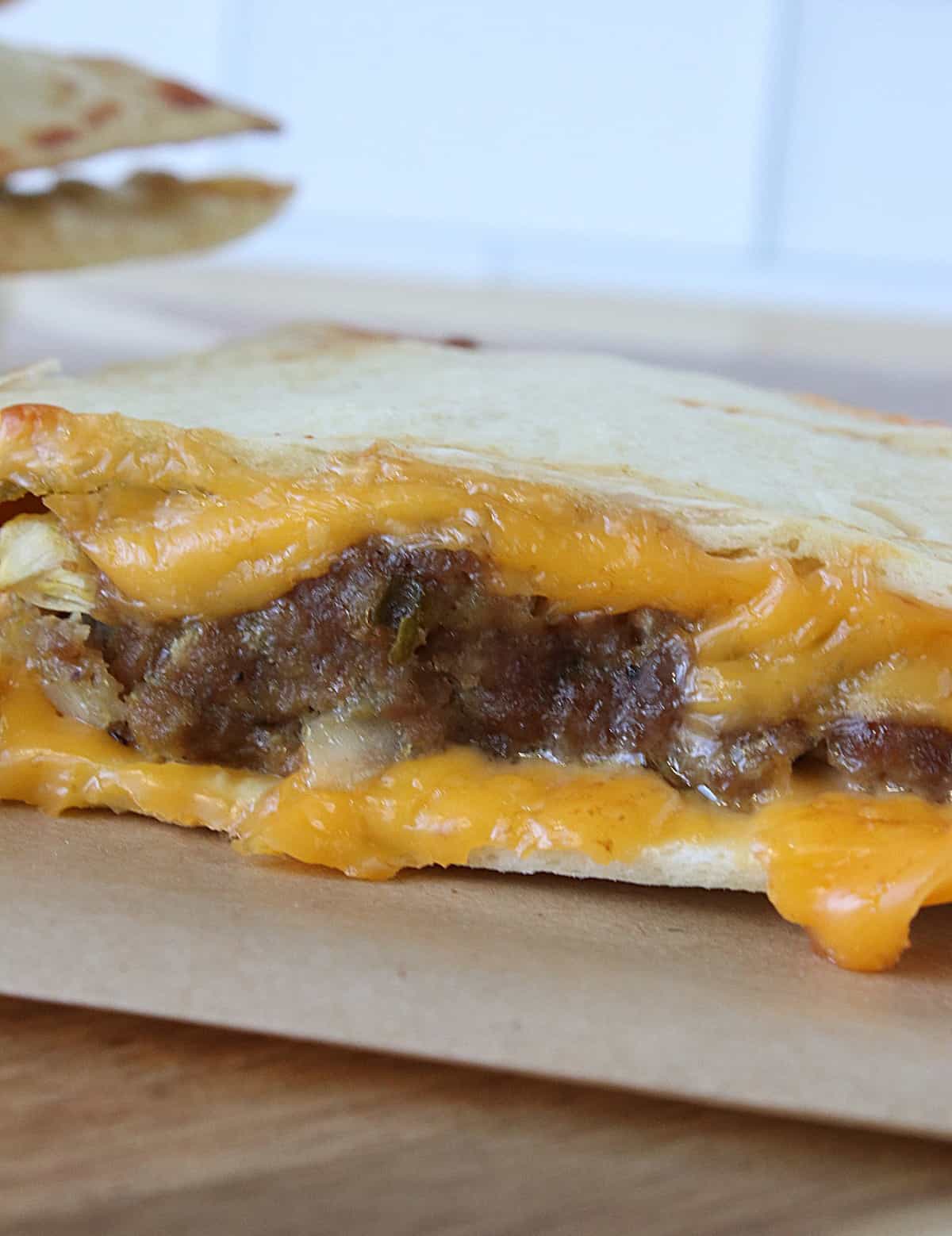 A ground beef burger cooked in a toasted flour tortilla with cheese. 