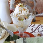 A glass parfait dish filled with Maple Pistachio Ice Cream with chopped pistachios on top.