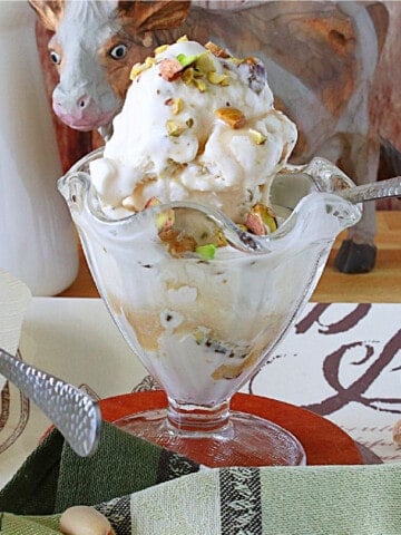 A glass parfait dish filled with Maple Pistachio Ice Cream with chopped pistachios on top.