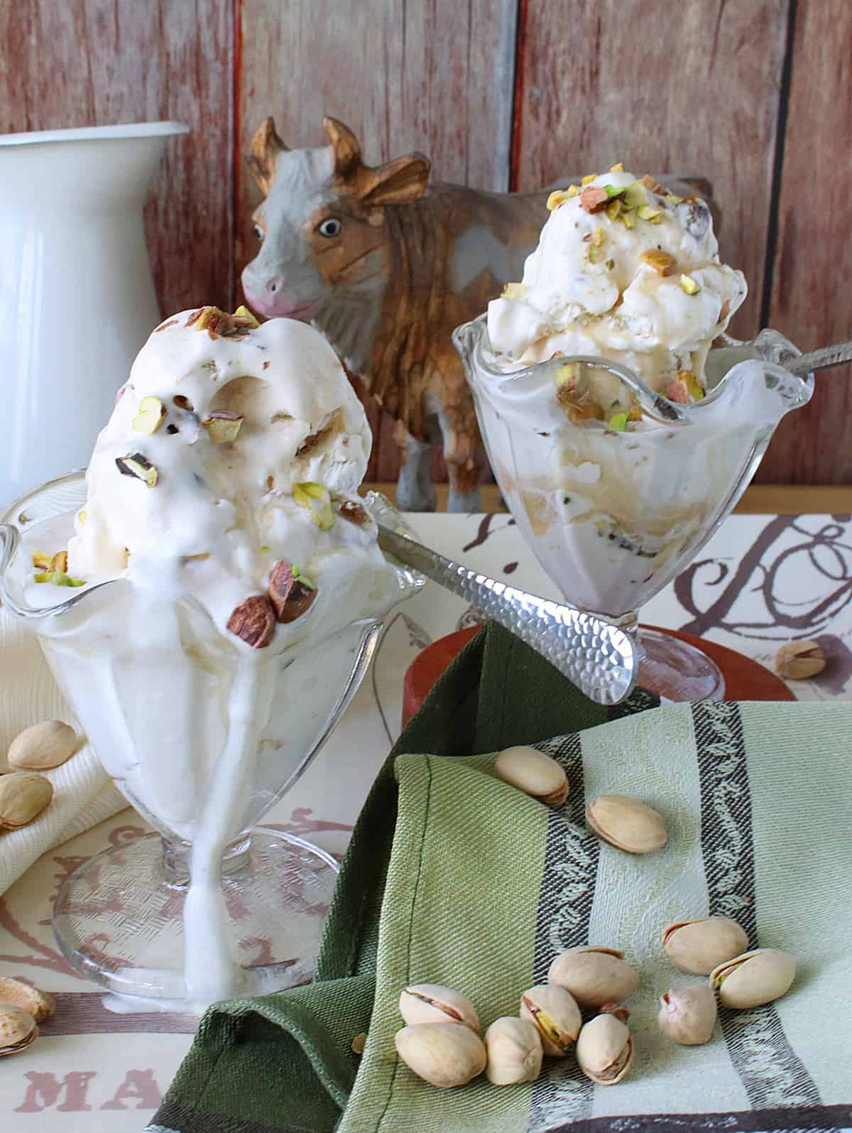 Two glass parfait dishes filled with Maple Pistachio Ice Cream and spoons.