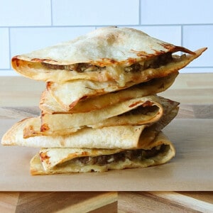 A stack to Burgerdillas on a wooden cutting board.