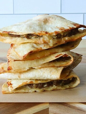 A stack to Burgerdillas on a wooden cutting board.