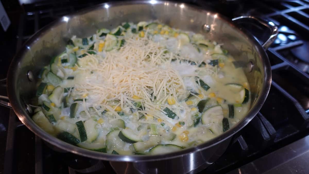 Cheese in a skillet with corn and zucchini.