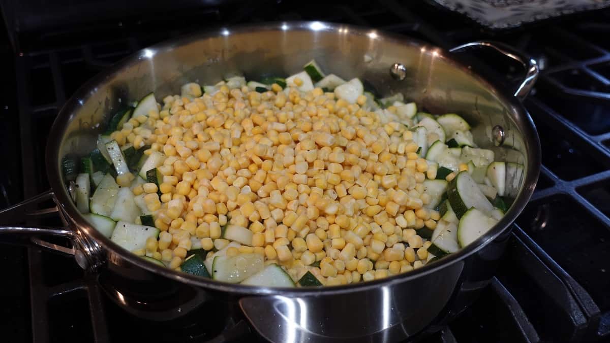 Chopped zucchini and corn in a skillet.