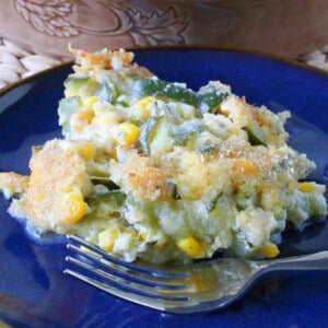 A serving of Zucchini Corn Gratin on a blue plate with a fork.