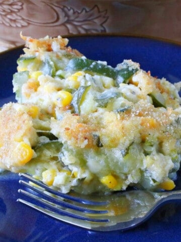 A serving of Zucchini Corn Gratin on a blue plate with a fork.