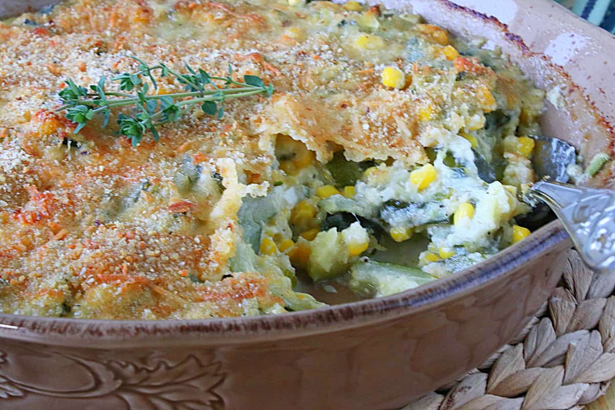 A tan casserole dish filled with Zucchini Corn Casserole with a golden-brown crust. 
