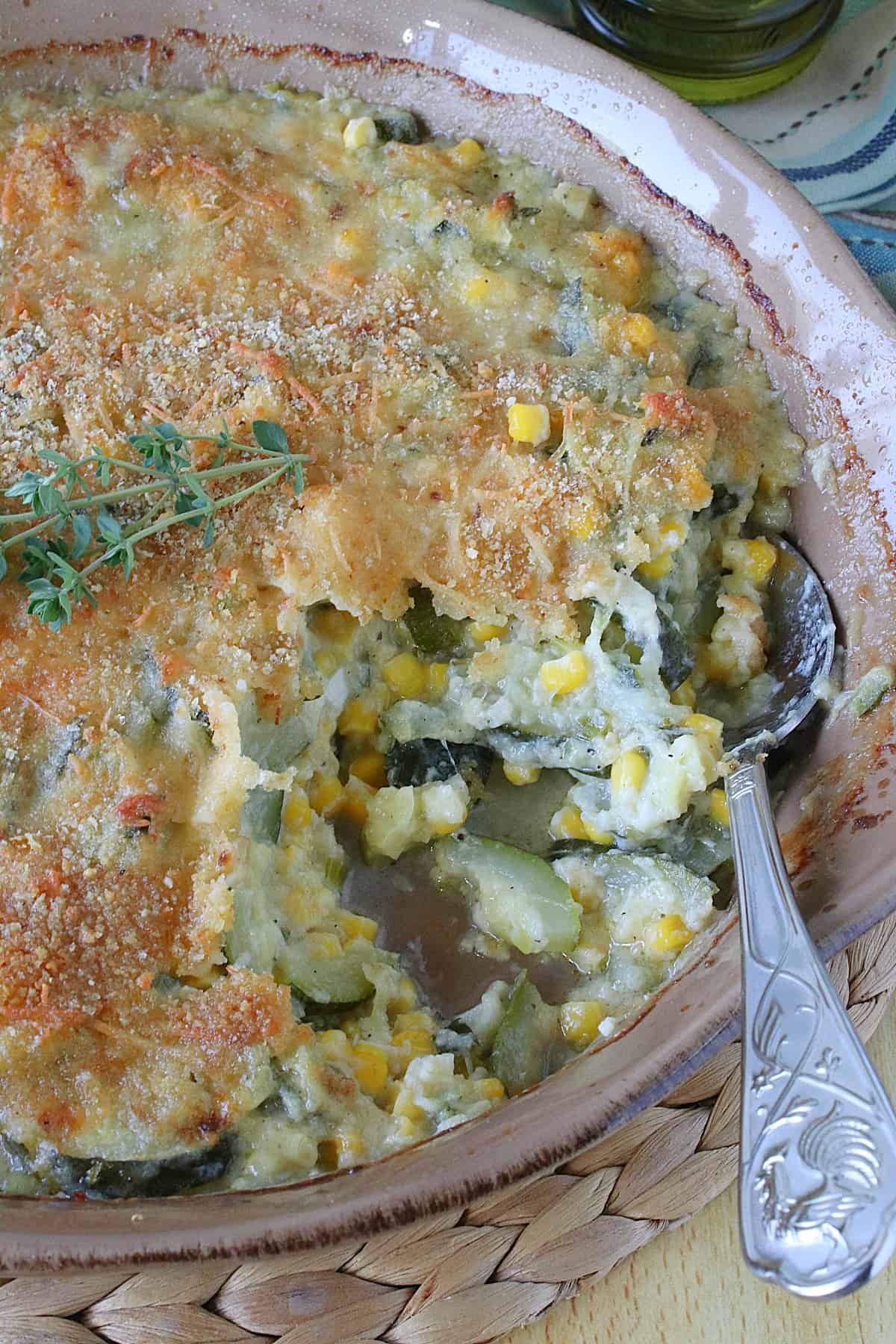 A serving spoon inside a Zucchini Corn Gratin Casserole.