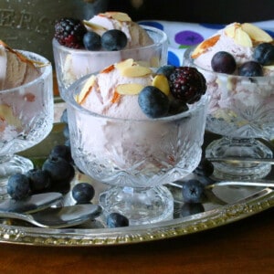 Glass parfait glasses filled with Blueberry Blackberry Gelato and topped with berries.