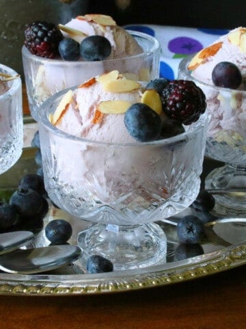 Glass parfait glasses filled with Blueberry Blackberry Gelato and topped with berries.