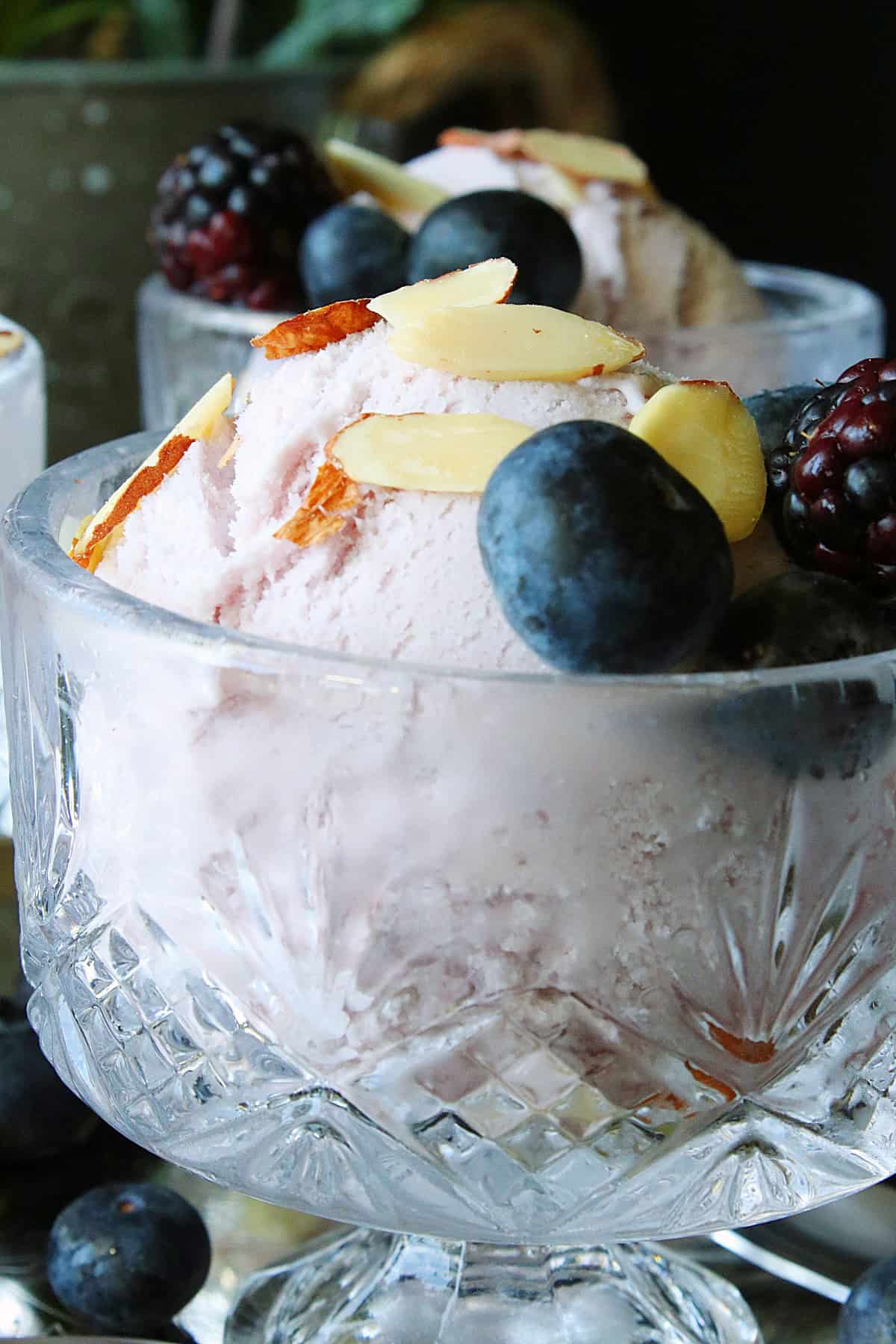 A glass dish filled with Blueberry Blackberry Gelato along with almond slivers and fresh berries.