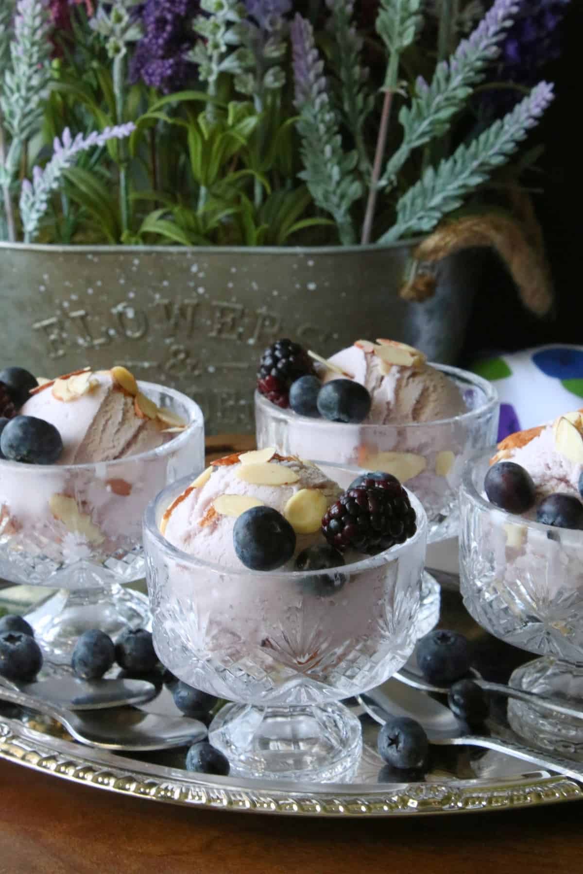 Four glass parfait dishes filled with Blueberry Blackberry Gelato along with fresh berries and almonds. 