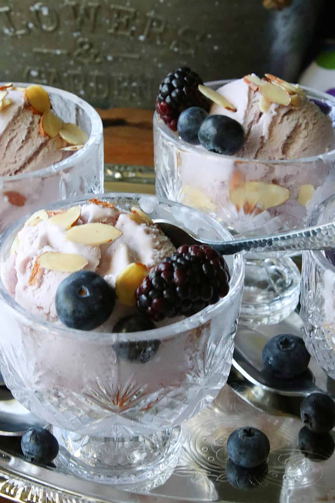 Pretty glass parfait dishes filled with servings of Blueberry Blackberry Gelato topped with berries and almonds. 