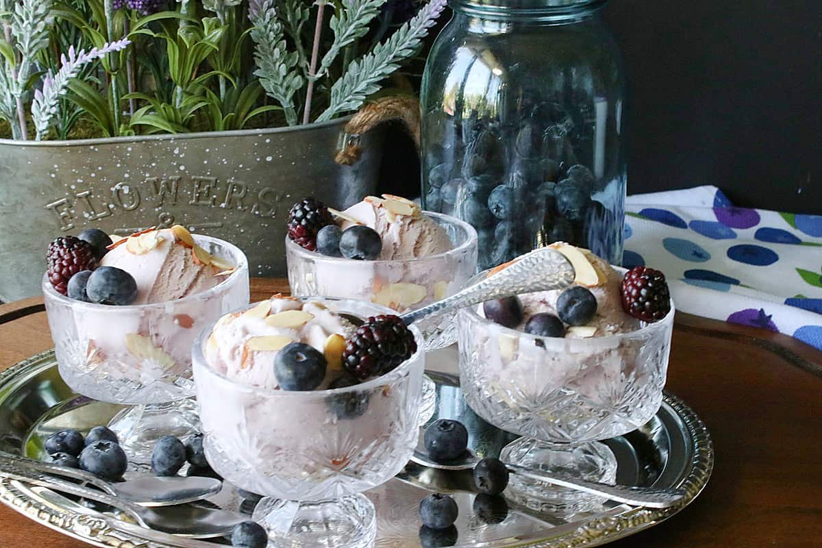 Four servings of Blueberry Blackberry  Gelato in pretty glass dishes on a silver tray.