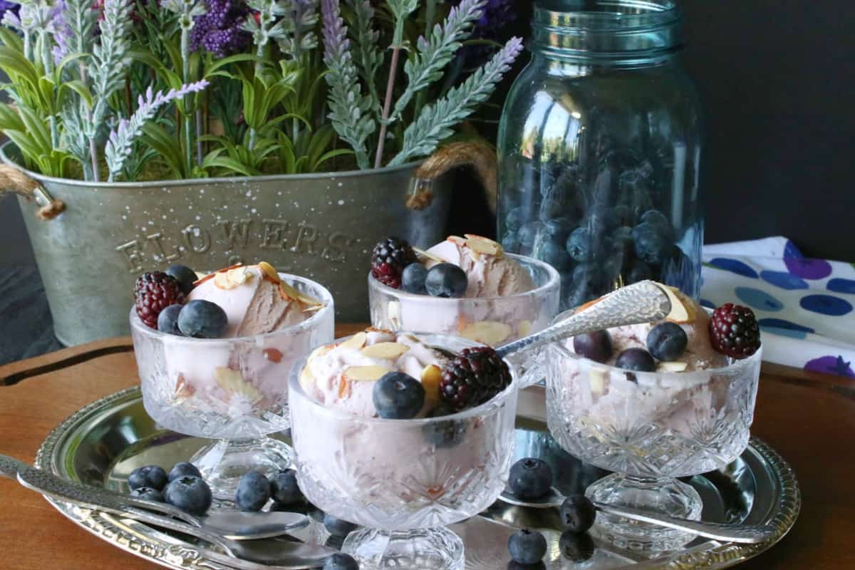 Four glass parfait dishes on a silver tray filled with Blueberry Blackberry Gelato Gelato and fresh berries.