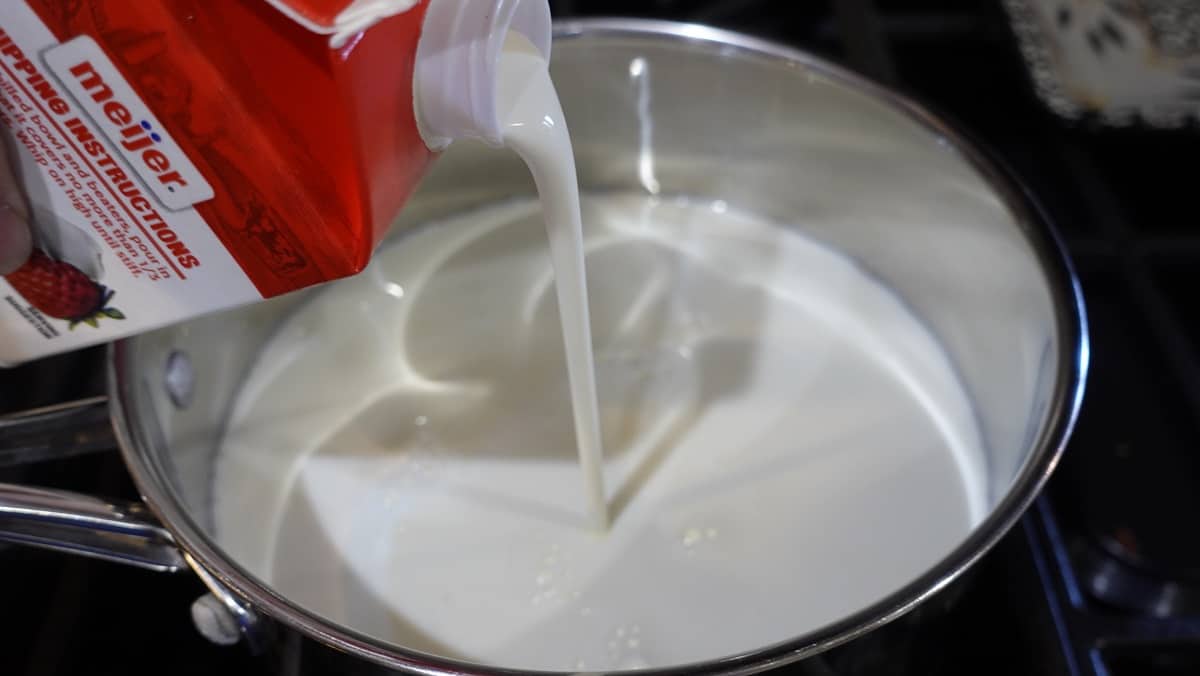 Heavy cream being poured into a saucepan.