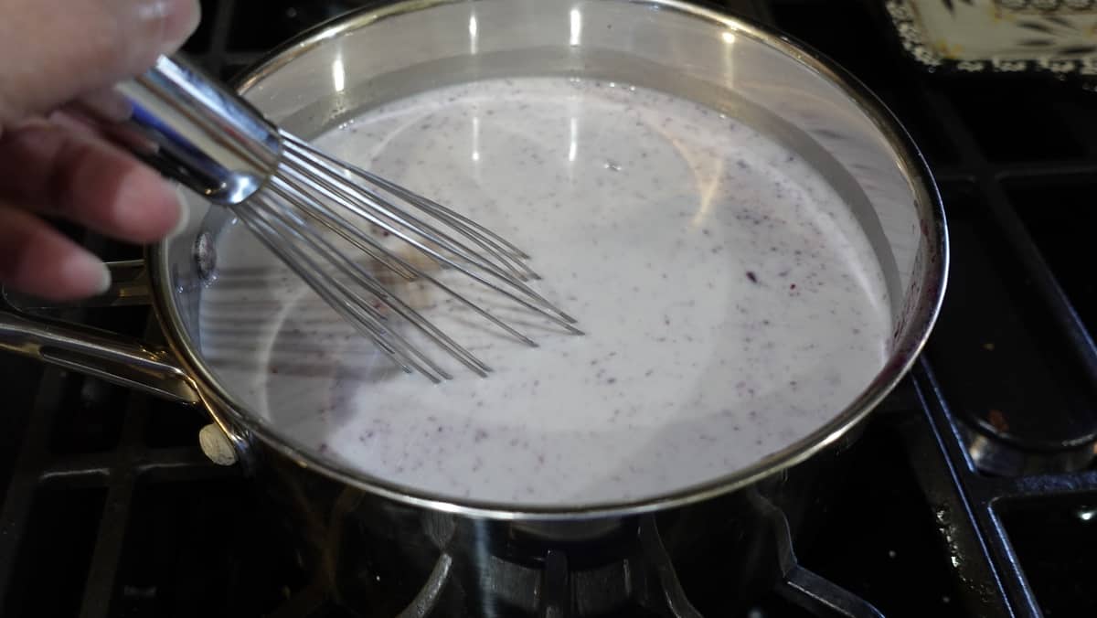 A whisk in a saucepan with gelato base.