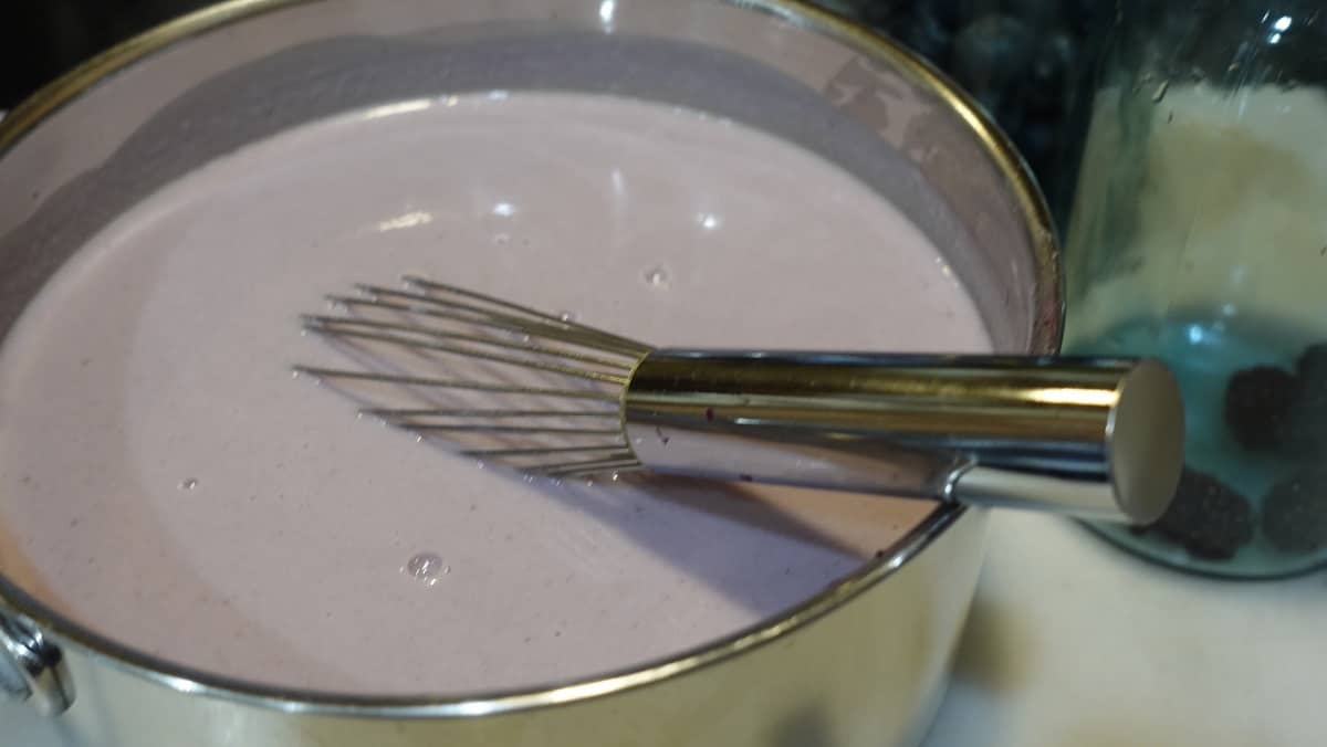 A violet gelato mixture in a saucepan with a whisk.