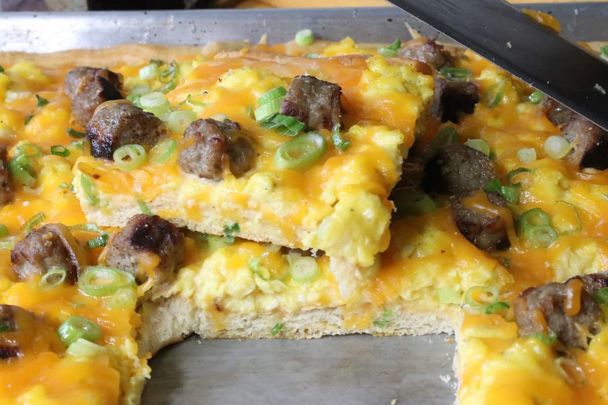 A slice of Egg Pizza with melted cheese and scallions on top.
