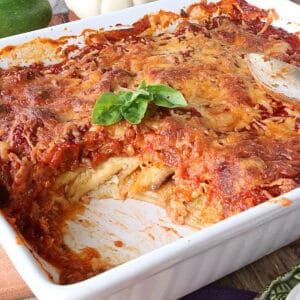 An Eggplant and Zucchini Lasagna in a white baking dish with basil leaves.