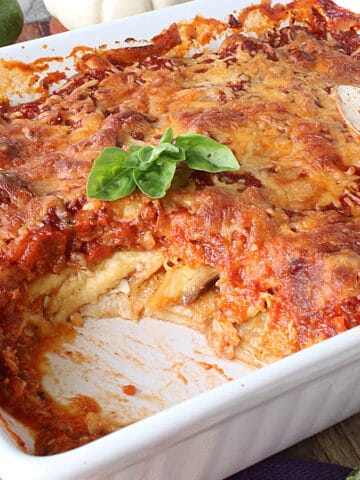 An Eggplant and Zucchini Lasagna in a white baking dish with basil leaves.