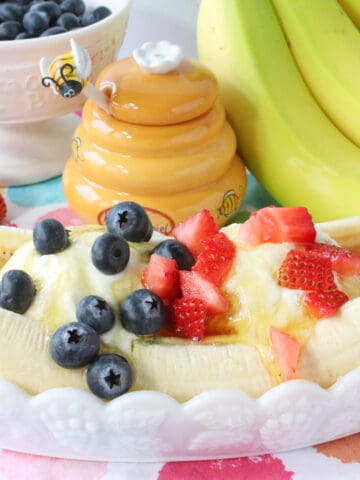 A Frozen Greek Yogurt Banana Split in a white dish with fresh berries on top.