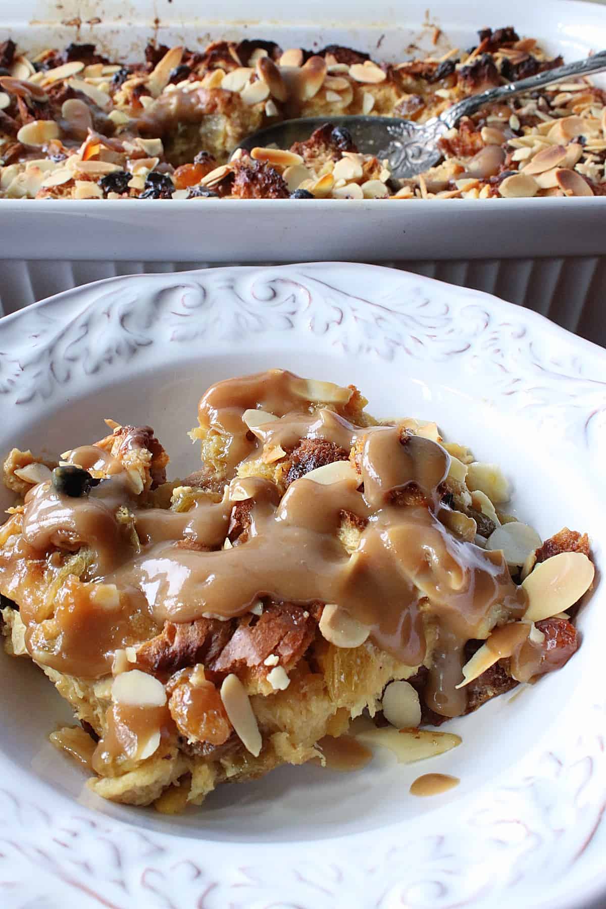 A serving of Panettone Bread Pudding with RumChata Sauce on top in a white bowl.