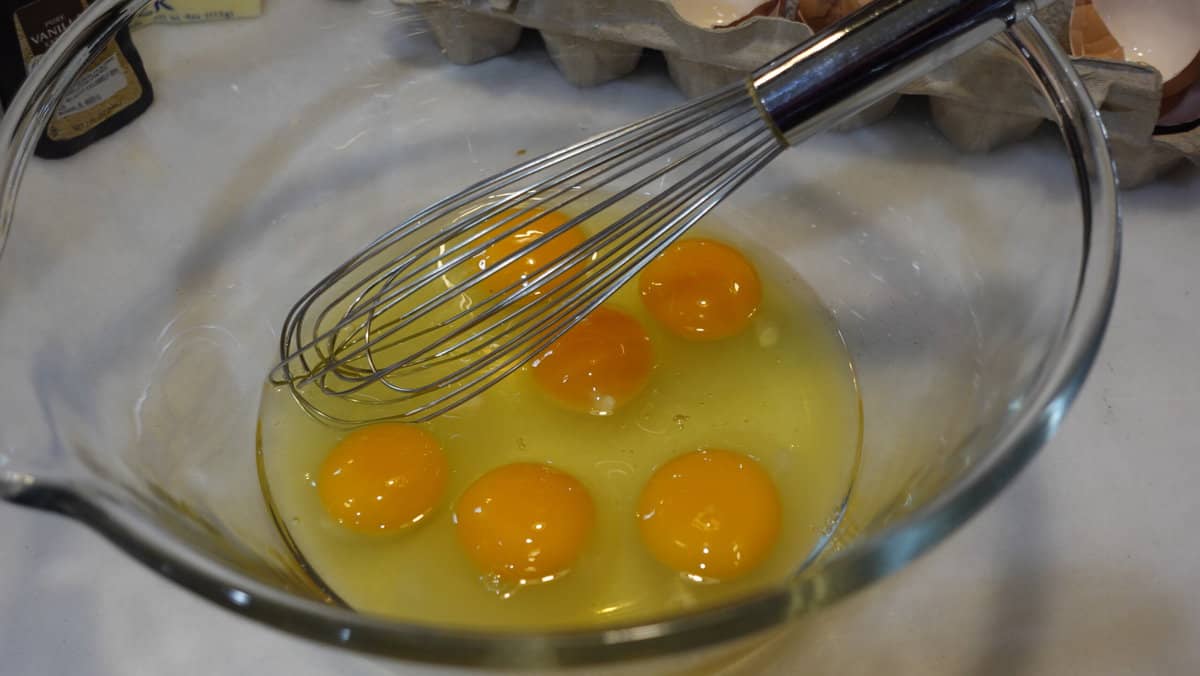 Egg in a glass bowl with a whisk.