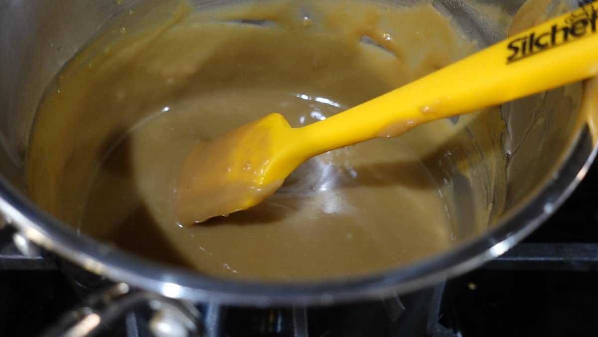 A caramel sauce in a saucepan with a spatula.