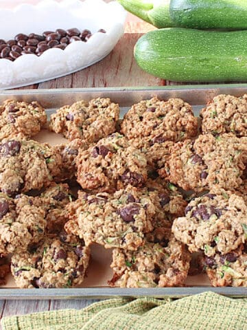 A baking sheet filled with Zucchini Oatmeal Cookies with chocolate covered raisins in the background.