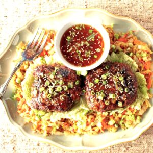 Two Crispy Duck Patties over Asian Cabbage with Orange sauce and scallions.
