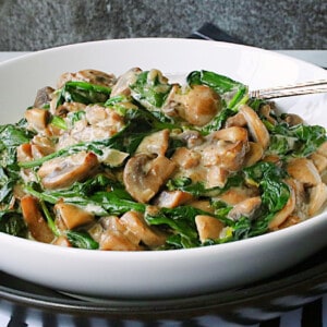 Creamy Mushrooms and Spinach in a white bowl with a serving spoon.