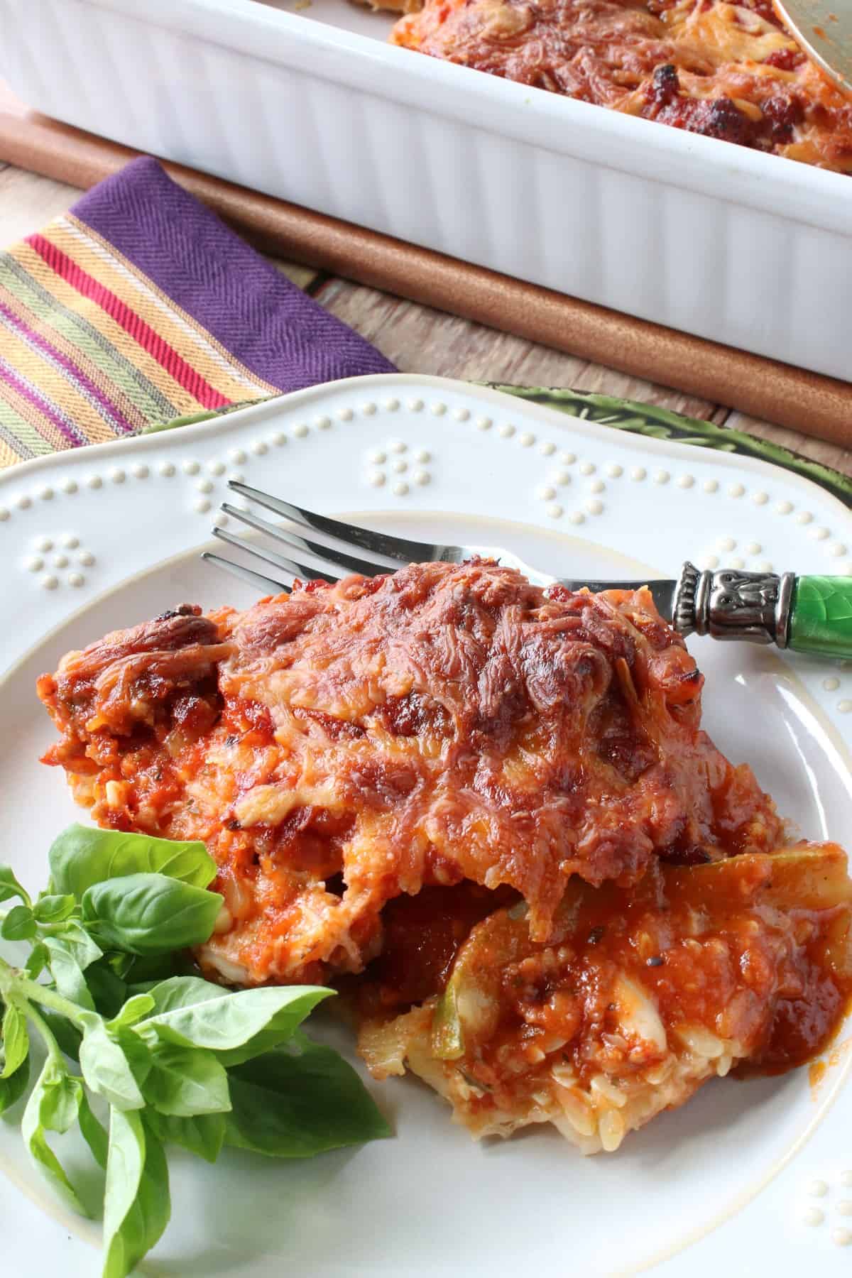 A plate of no noodle Eggplant and Zucchini Lasagna with fresh basil on the side. 