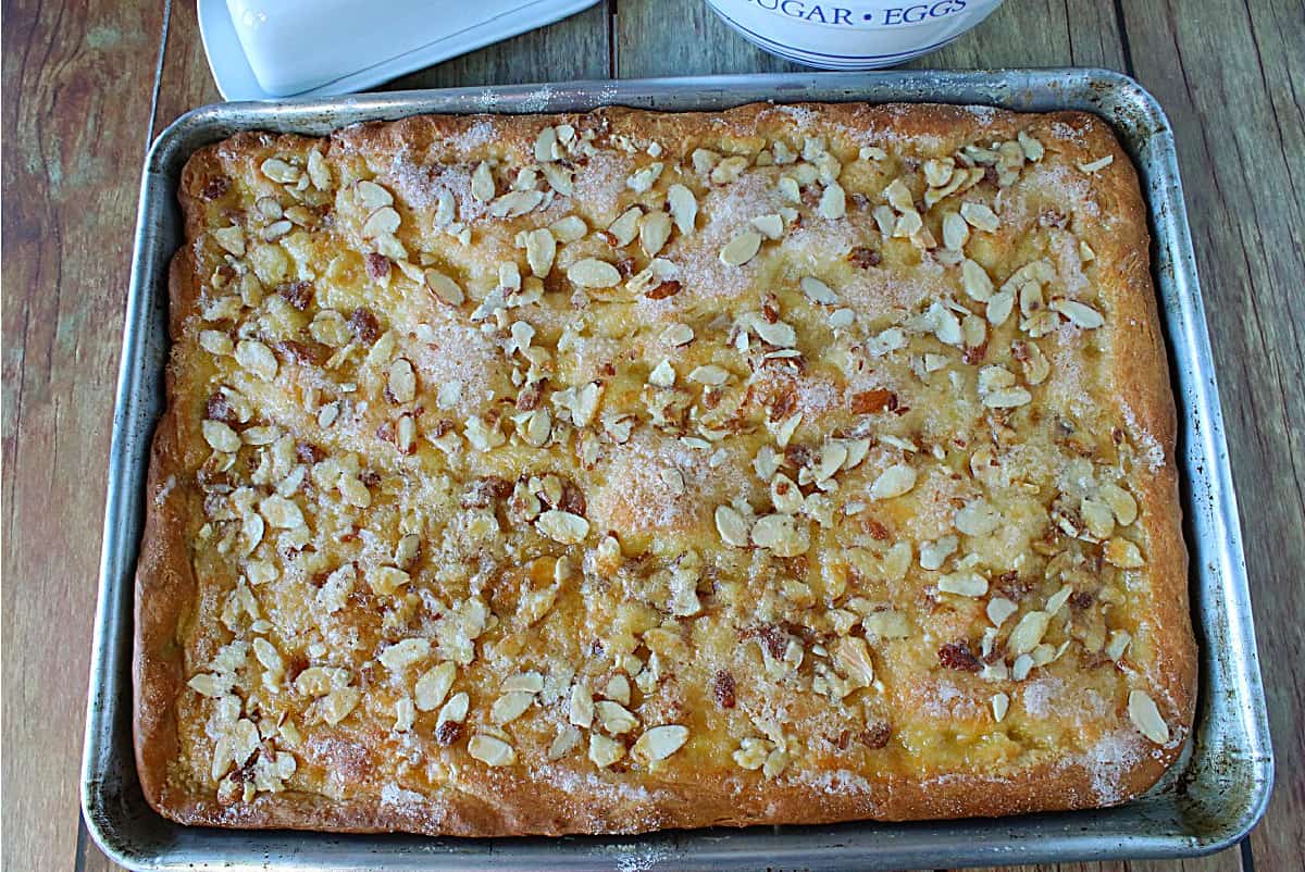 A sheet tray filled with golden brown German Zuckerkuchen topped with almonds and sugar.