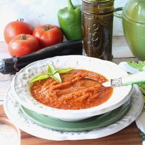 A serving of Roasted Tomato and Vegetable Soup in a bowl with fresh veggies in the background.