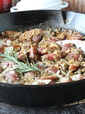 Vesuvio Potatoes and Gravy in a skillet with fresh rosemary.