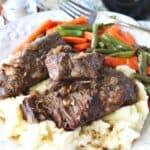 A serving of Oven Braised Beef Short Ribs on a plate with mashed potatoes.