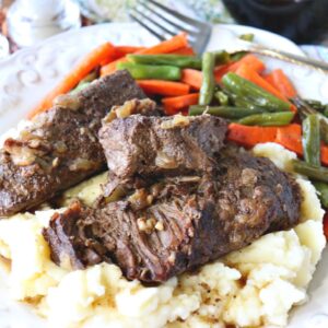 A serving of Oven Braised Beef Short Ribs on a plate with mashed potatoes.