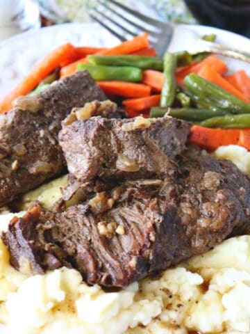 A serving of Oven Braised Beef Short Ribs on a plate with mashed potatoes.