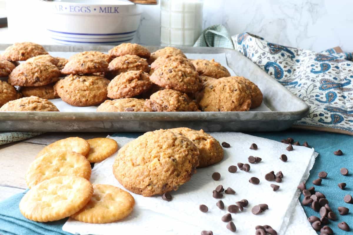 A baking sheet and napkin loaded with Butterscotch Ritz Cookies with a glass of milk in the background.